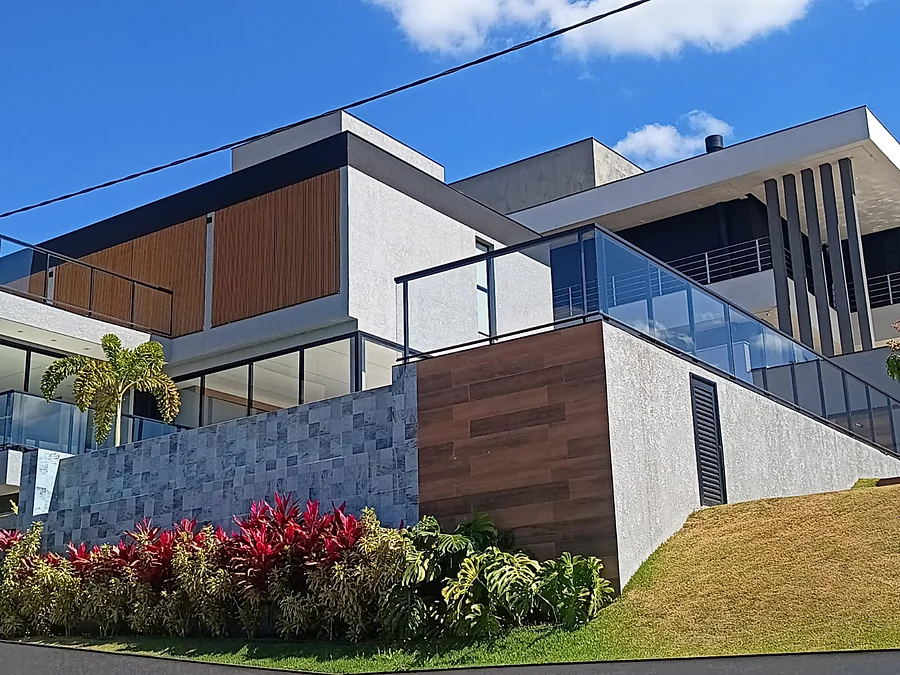 Sobrado entregue, com fachada em pedra, ripado de madeira e guarda-corpo de vidro